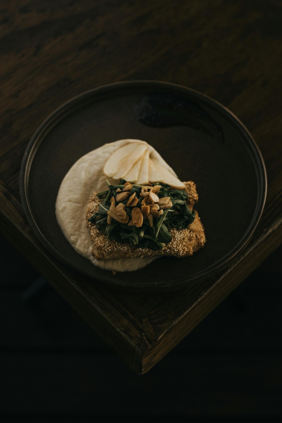 Signature plated dish at Bosq — Michelin Star tasting menu course, dark ceramic, single-point light