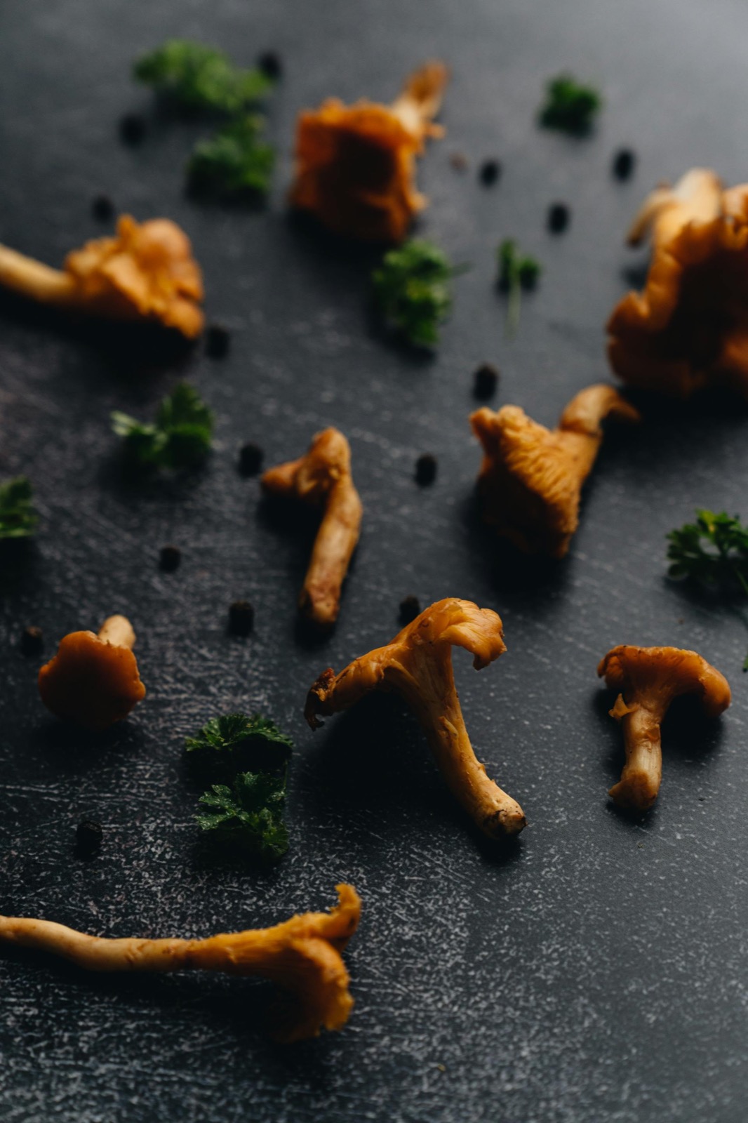 Foraged chanterelle mushrooms and parsley on dark slate